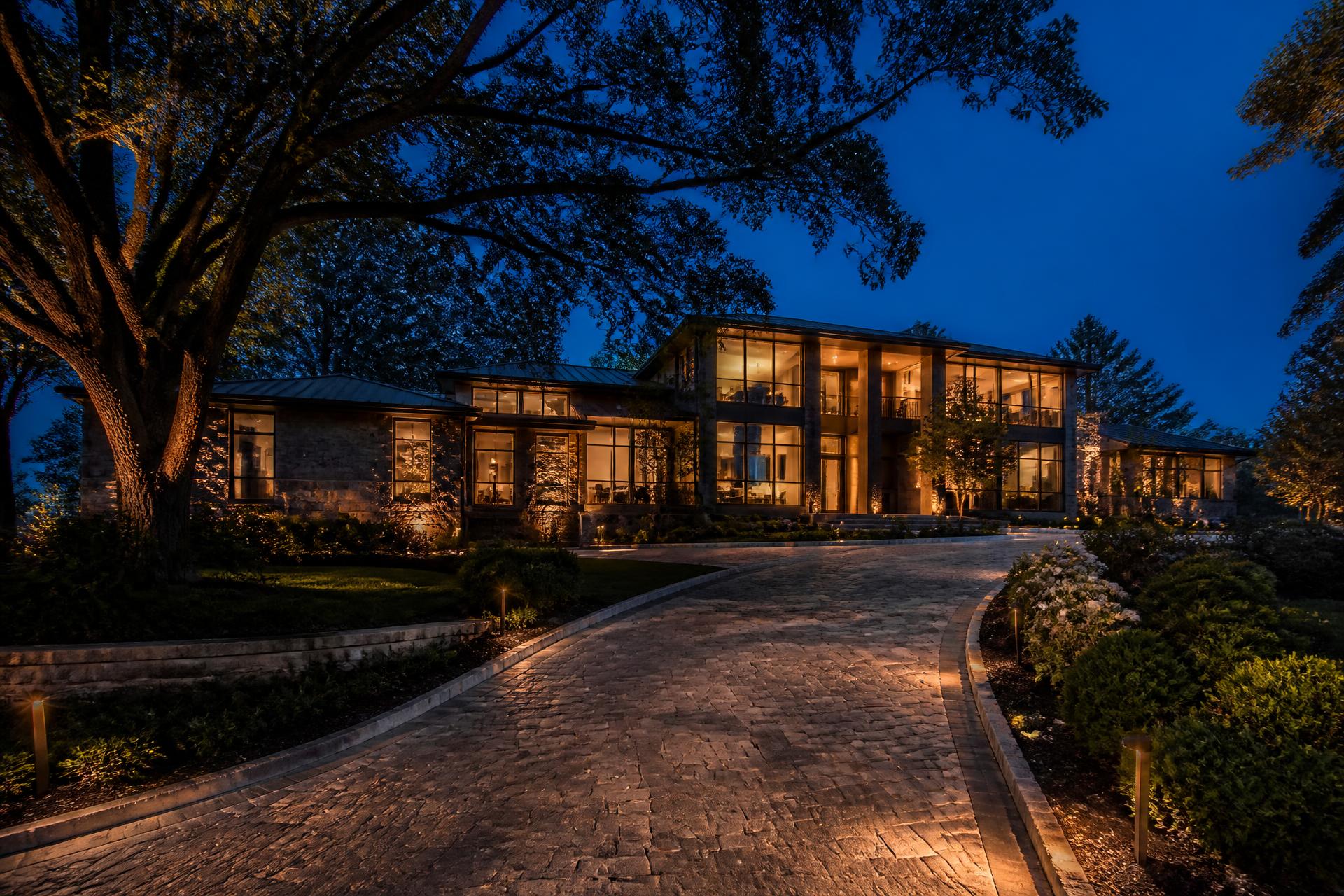 Modern luxury estate at dusk with warmly lit windows
