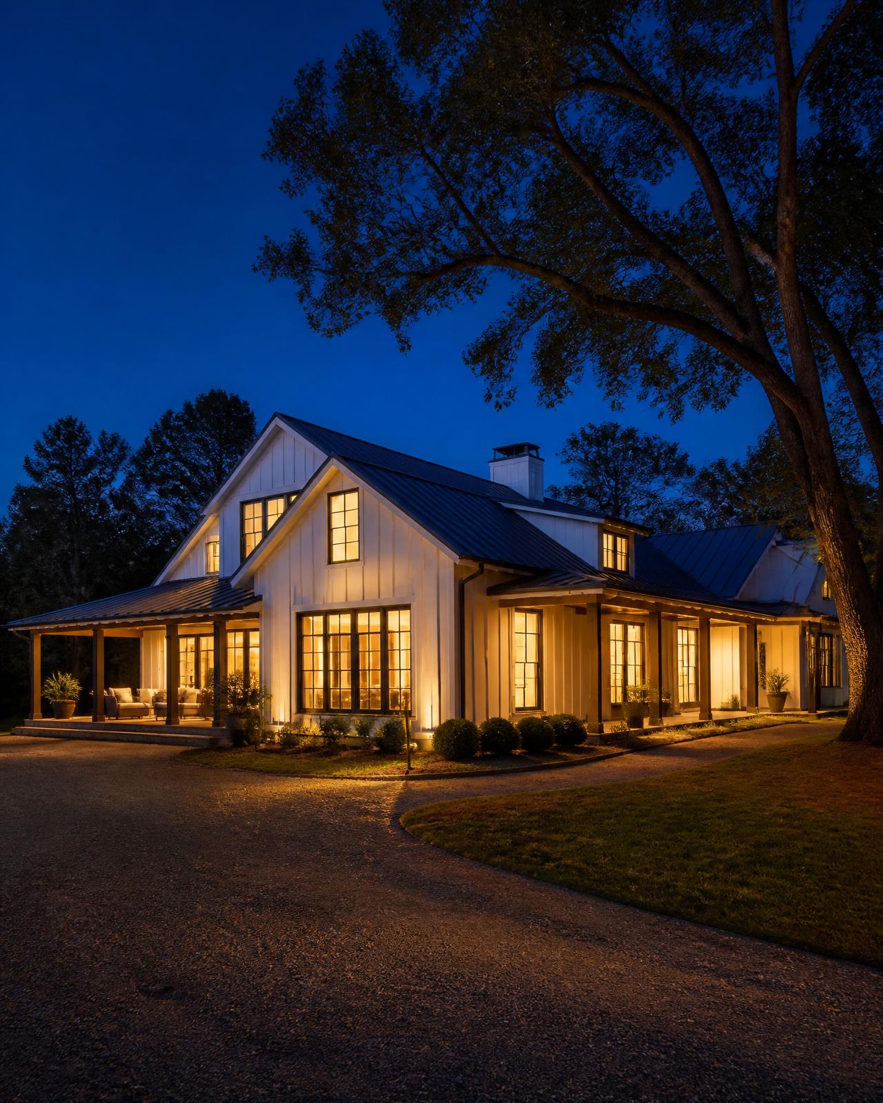 Modern luxury farmhouse glowing warmly at dusk